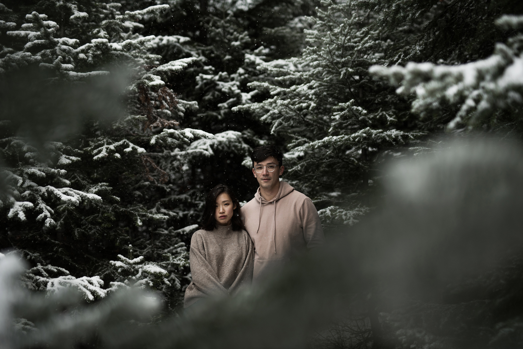 couple together in thick snowy pines