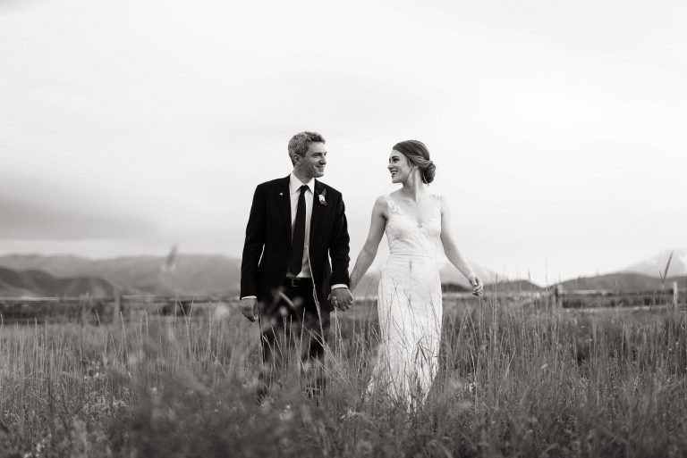 Lovers holding hands and walking through a mountain field.