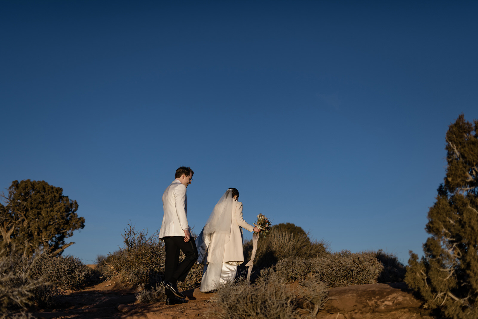 Bride and groom walk up a southern Utah hill.