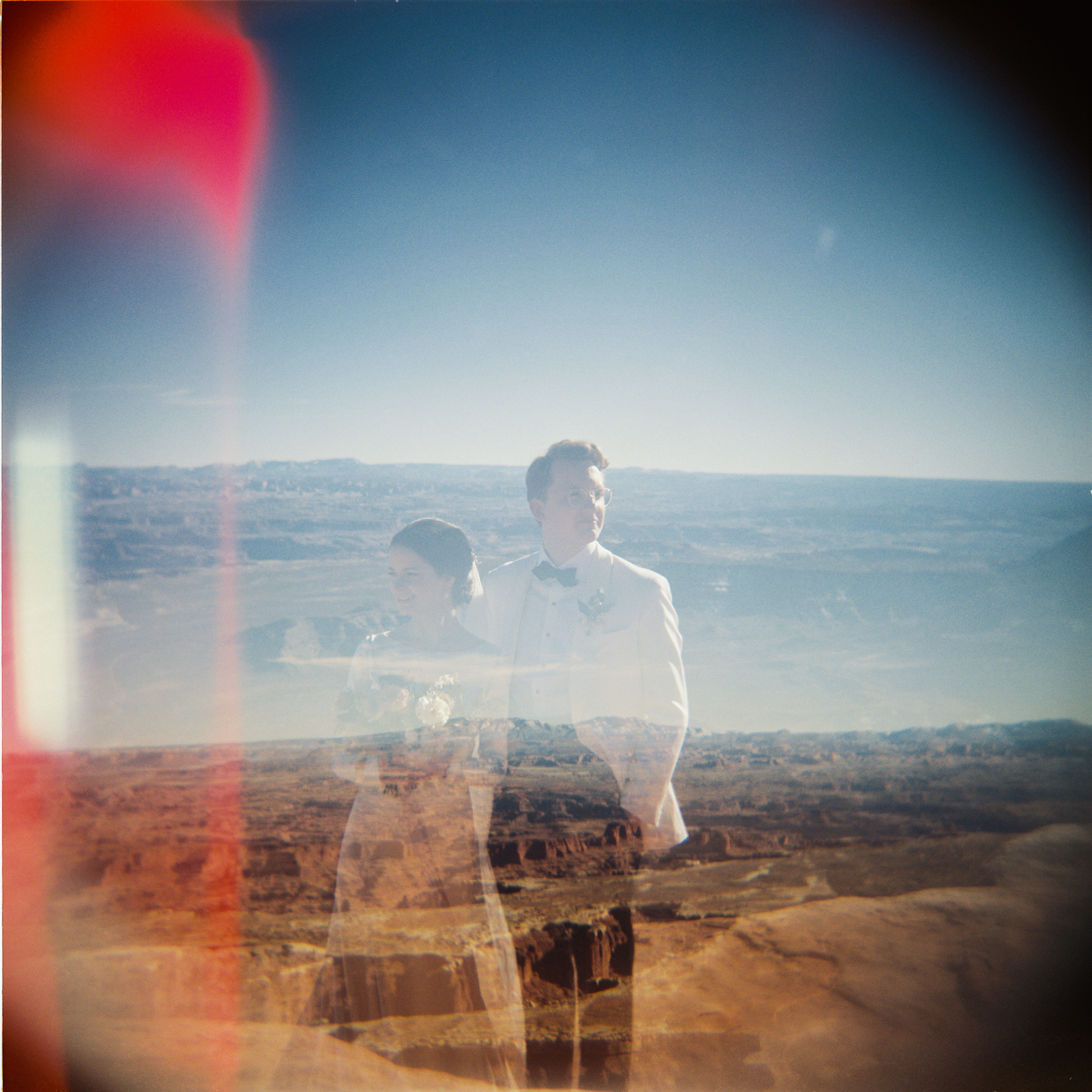 Double exposure film photo of bride and groom superimposed over the southern Utah dessert landscape.