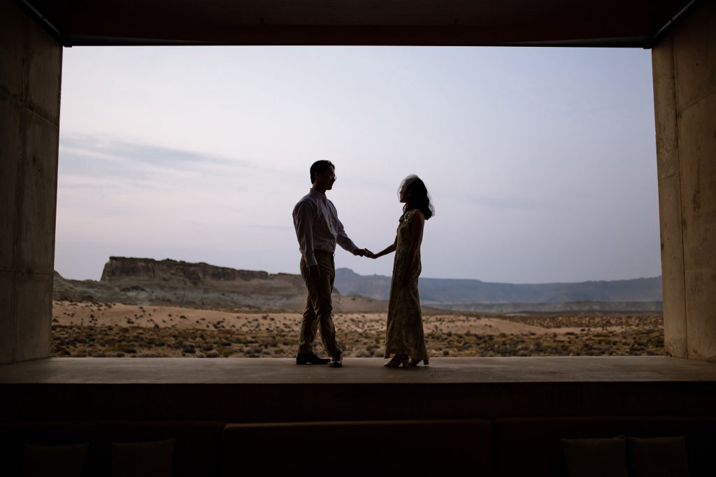 Silouetted couple holding hands with the dessert in the backgound.