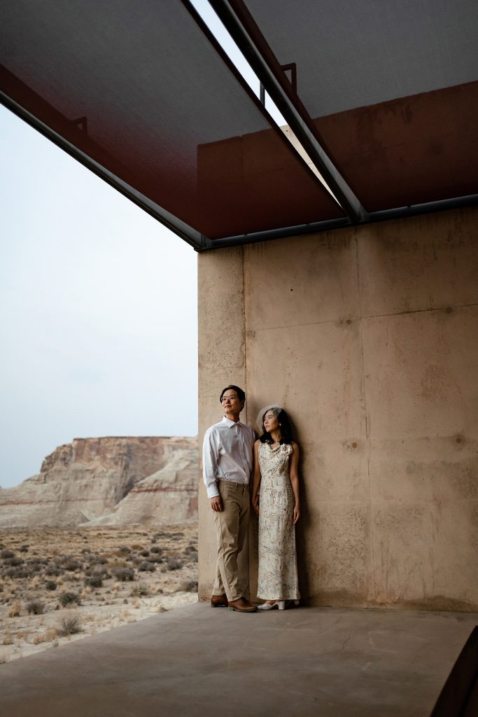 Couple standing together in the impressive Amangiri architecture with dessert plateaus in the distance.