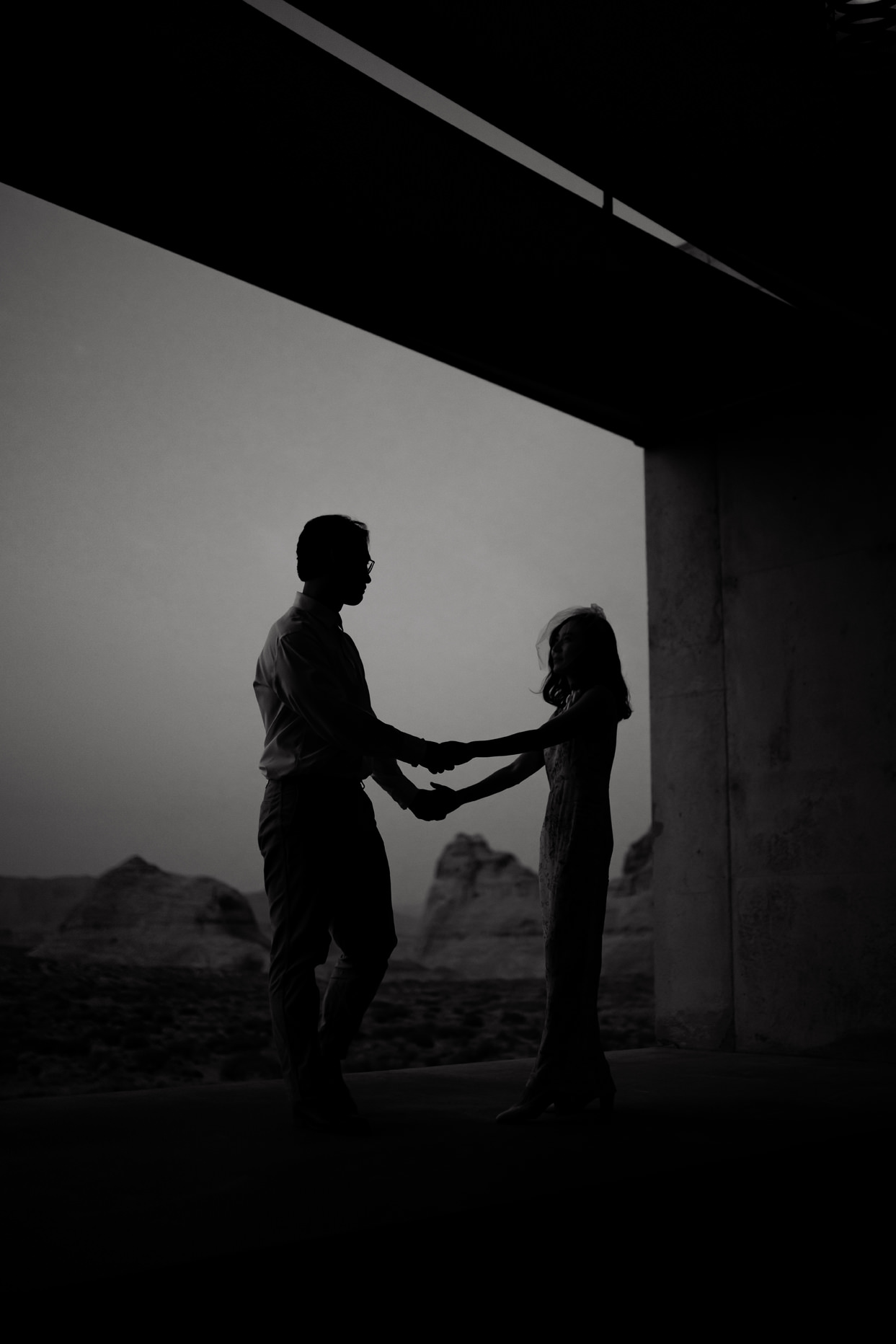 Dark black and white of couple standing on the edge of their Amangiri room.