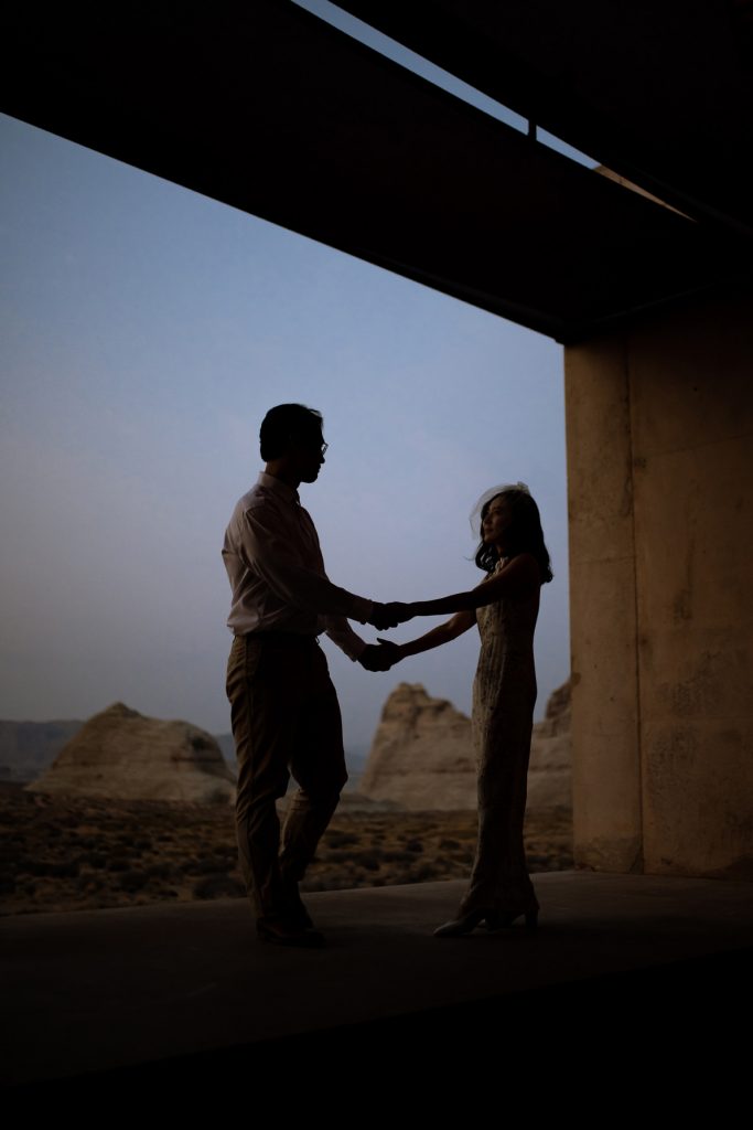 Lovers holding each others hand at sunset on the balcony of their Amangiri room.