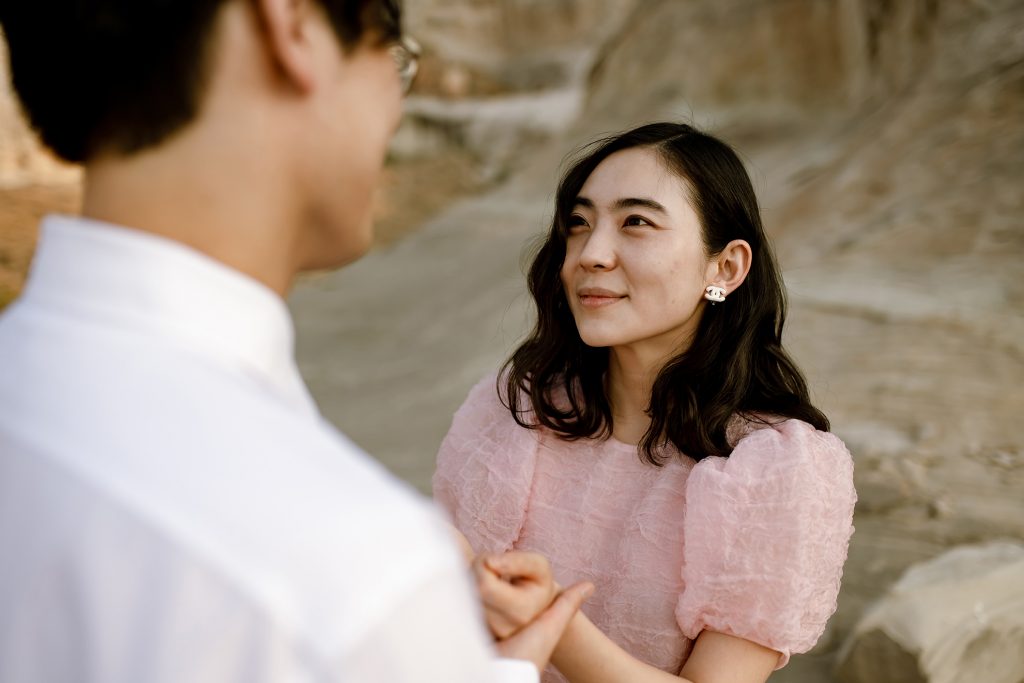 Woman wearing pink and wearing Chanel earings looks towards her new husband.