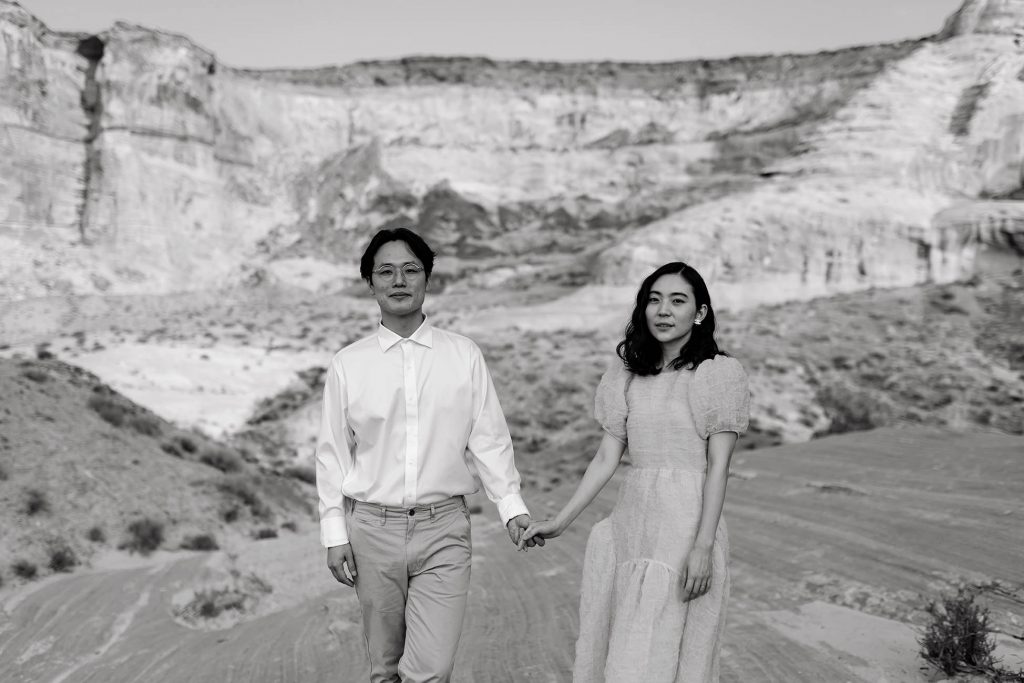 Man in a white button up and khakis and his wife wearing a pink dress looking at the camera.