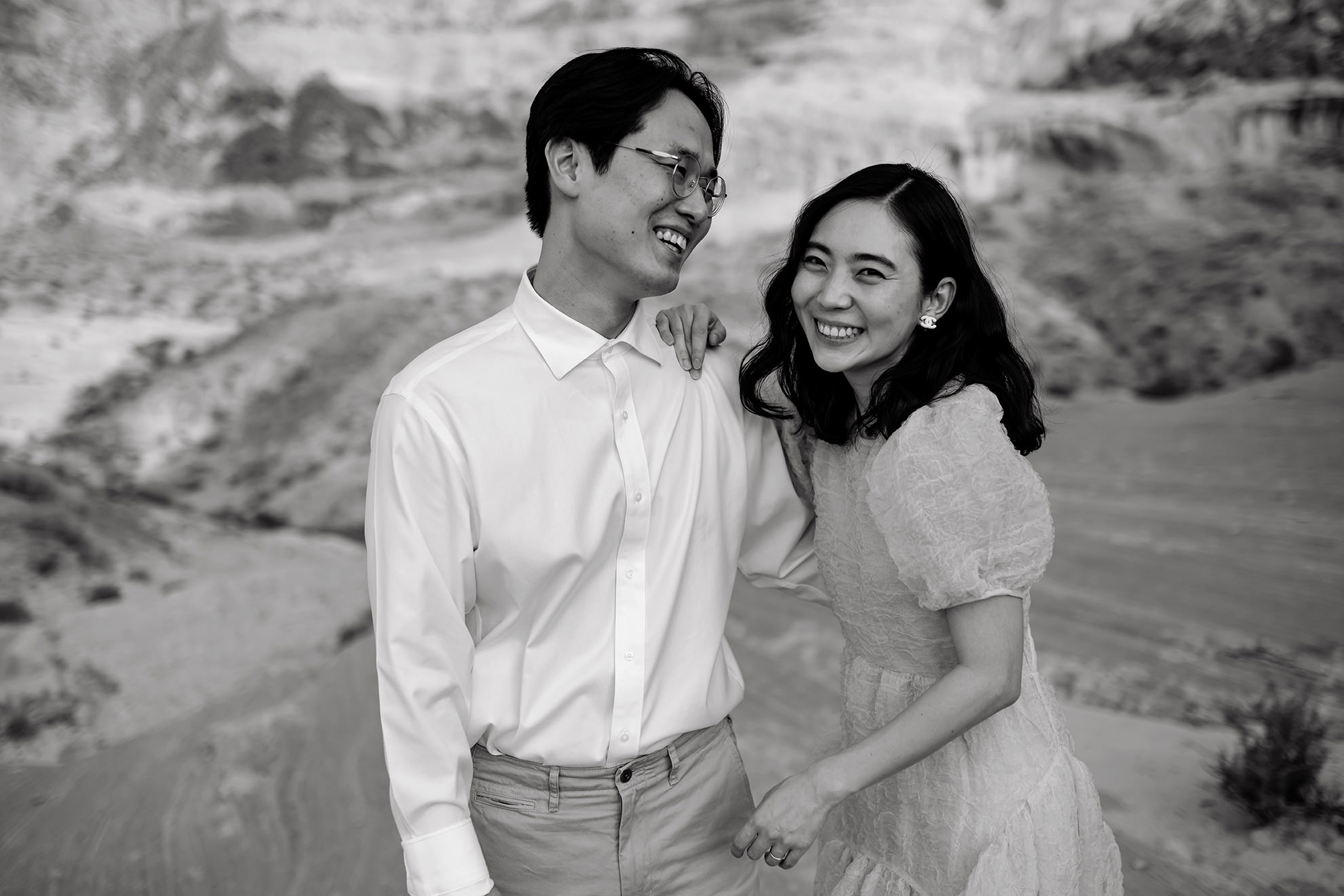 Husband and wife laugh with each other in black and white.