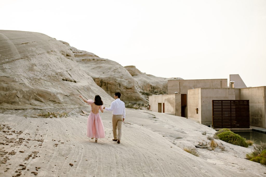 Woman in pink points off into the desert towards the rocky hills.