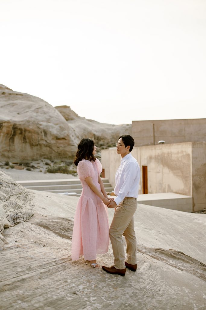 Woman in pink stands hand in hand with her new husband at the edge of Amangiri.