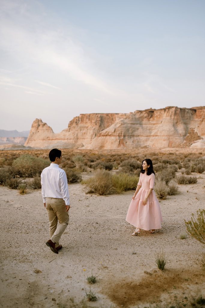 Husband and wife walk towards each other in a small desert clearing.