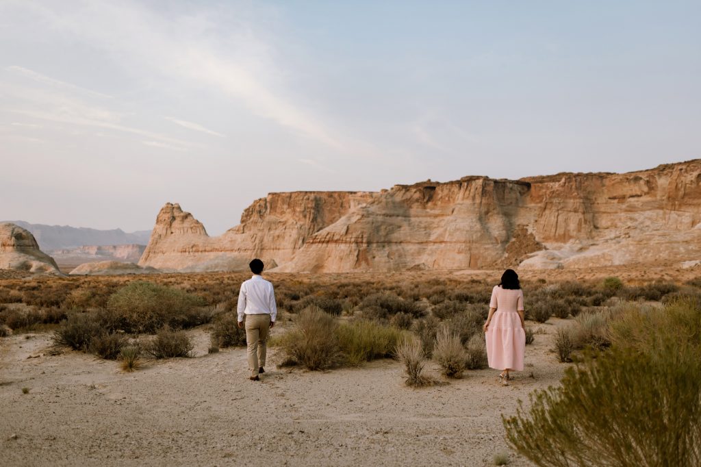 Husband and wife walk towards the desert bluffs.