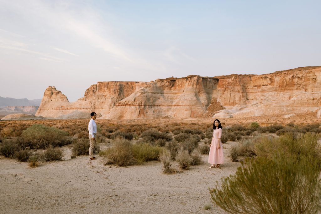 Pretty lady in pink dress looks towards the camera while her new husband looks at her admiringly.