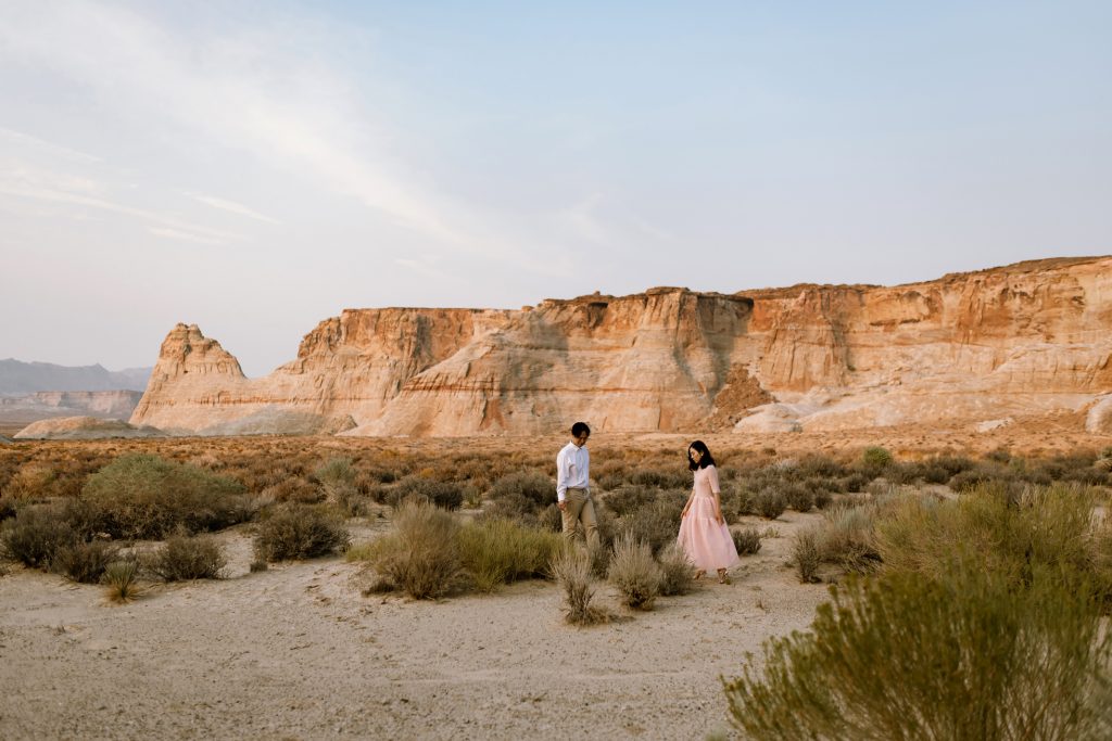 New husband and wife looking towards the ground with the Southern Utah desert.