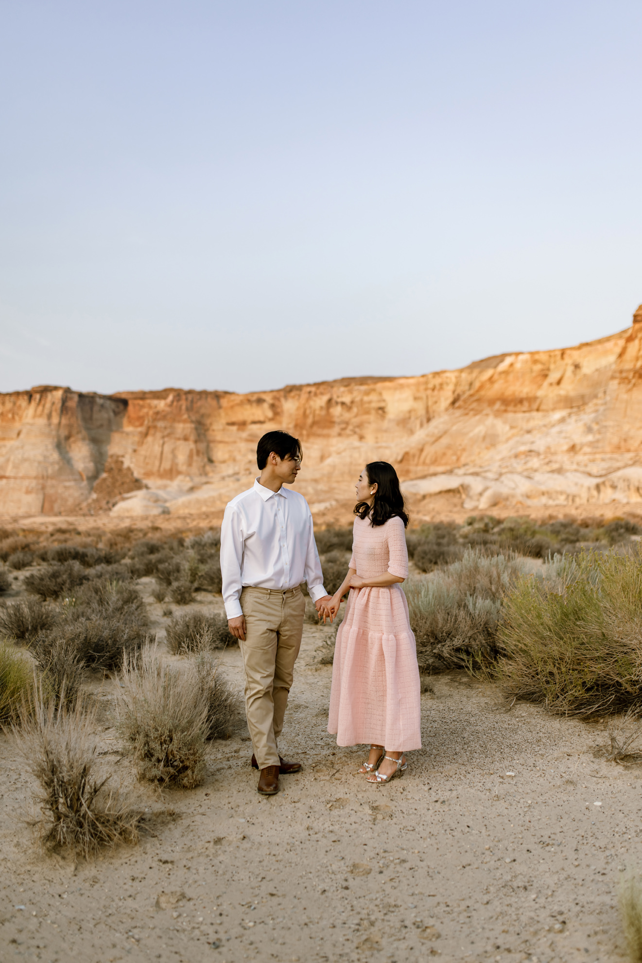 Portrait and new husband and wife standing hand in hand in the southern USA desert looking at each other.