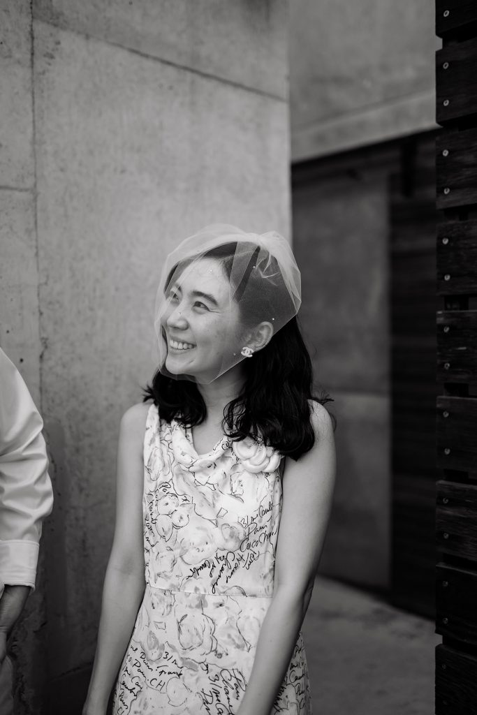 Bride smiles at her husband through her veil covered face.