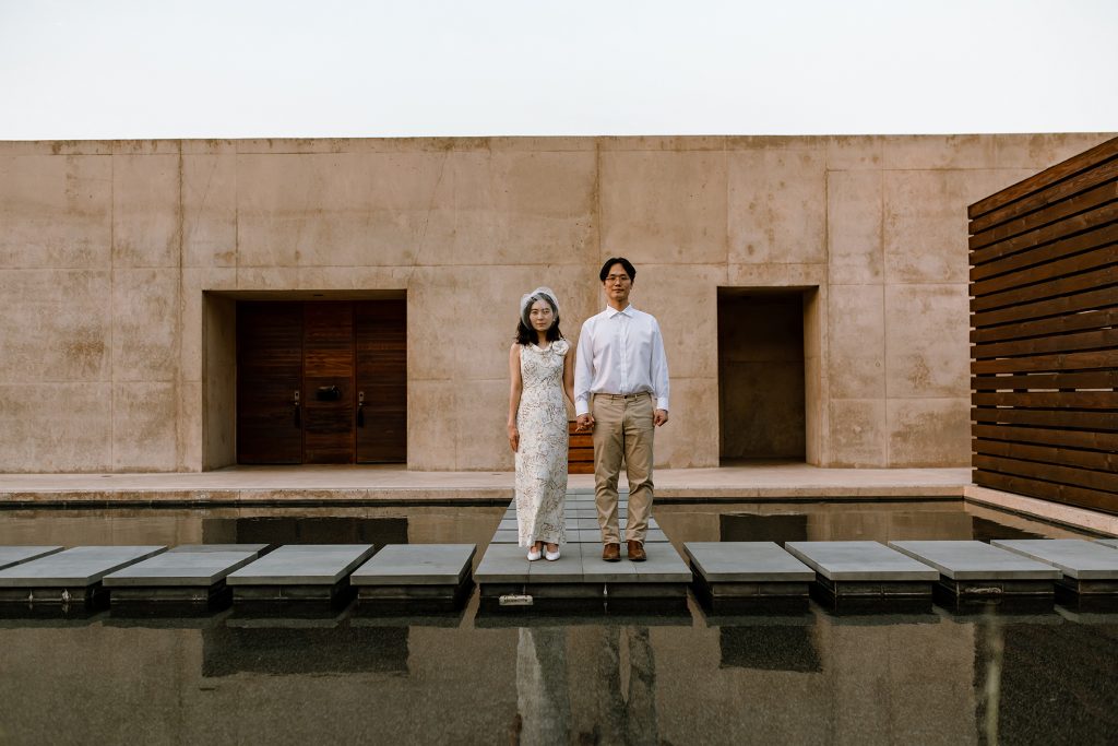 New husband and wife look at the camera on a watery path at Amangiri.