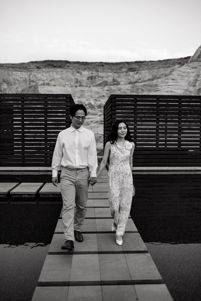 Husband and wife hold hands while walking through Amangiri courtyard.