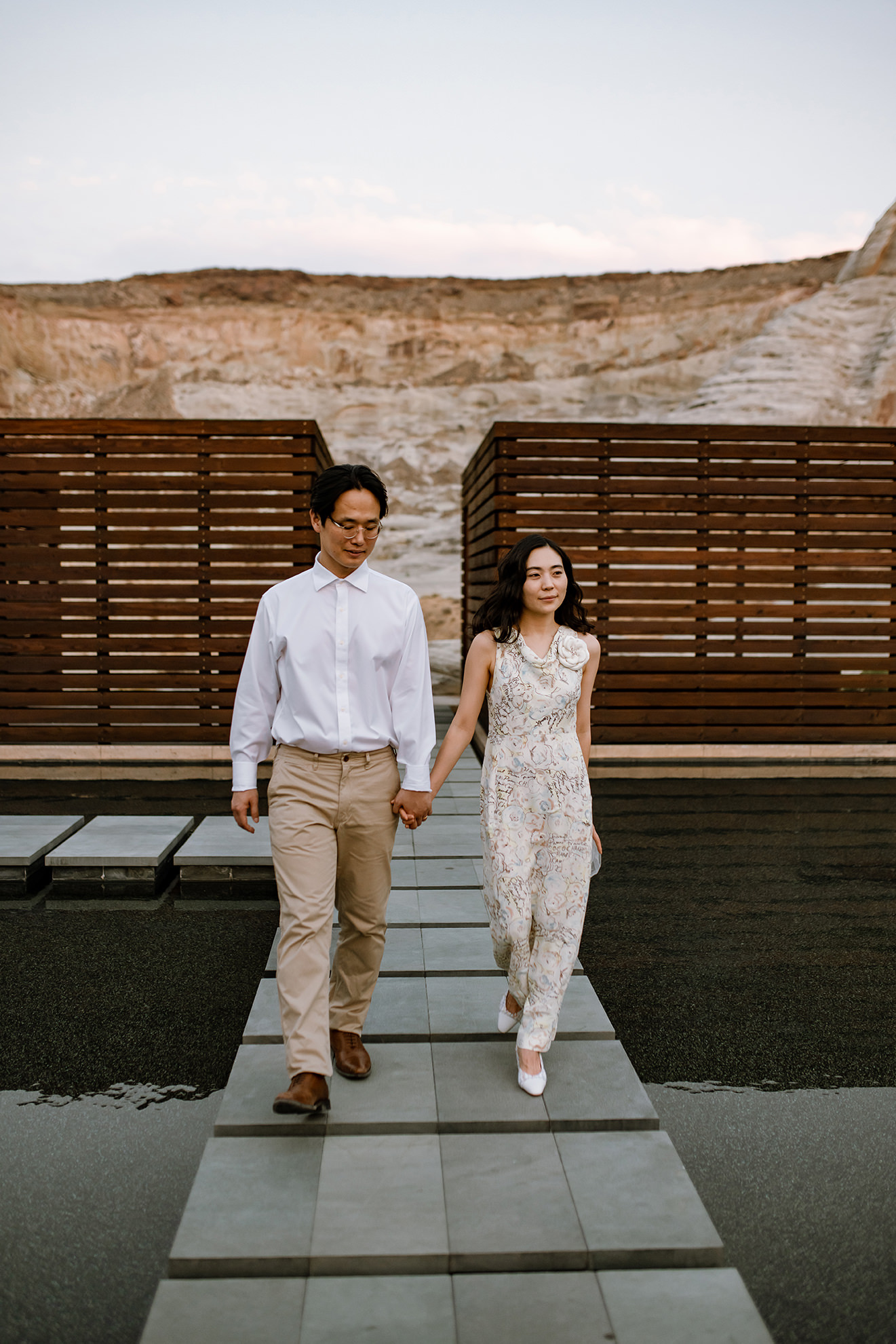 Husband and wife hold hands while walking through Amangiri courtyard.