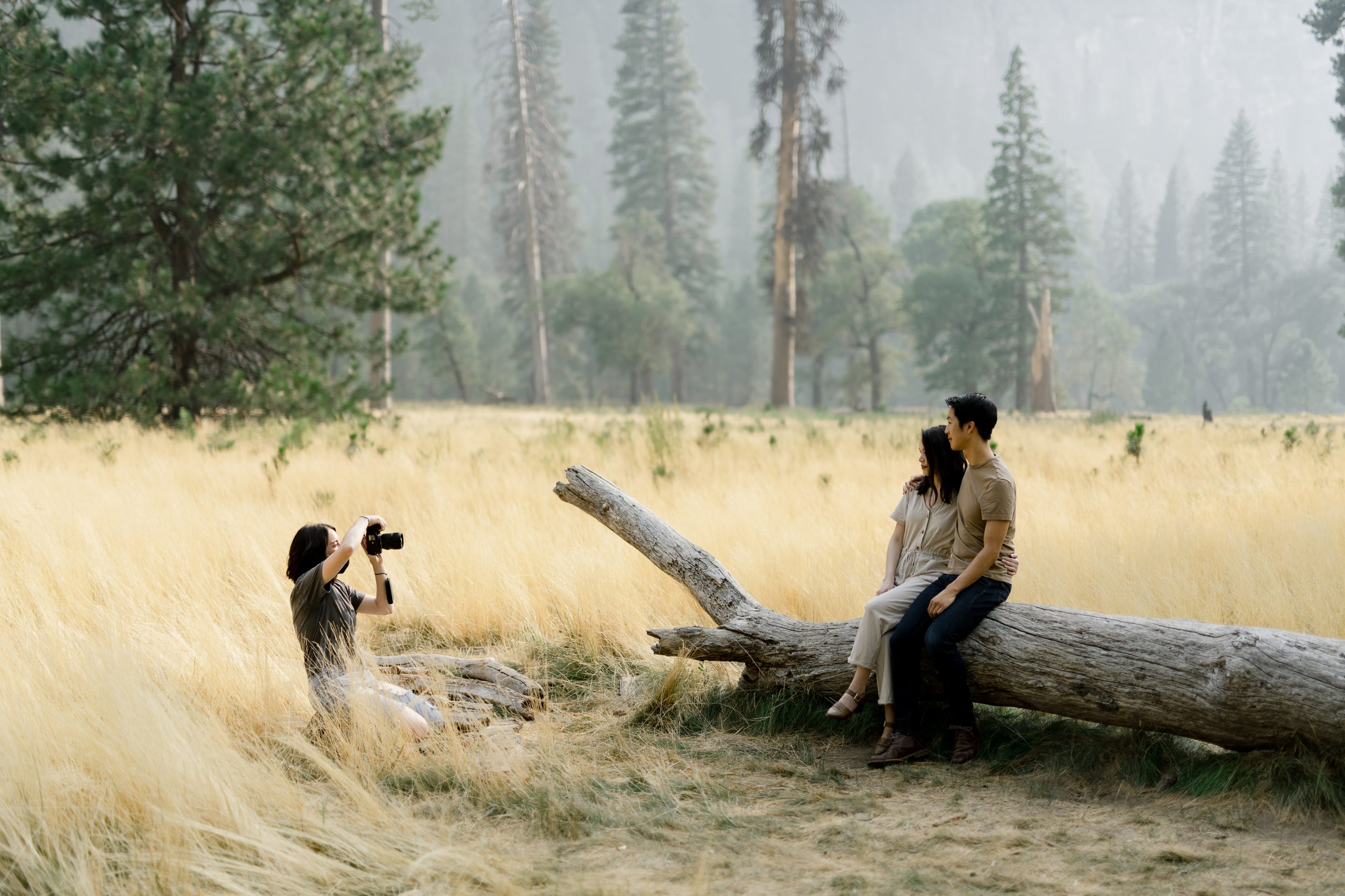 Elisha Braithwaite taking a photo of her couple sitting on a log.