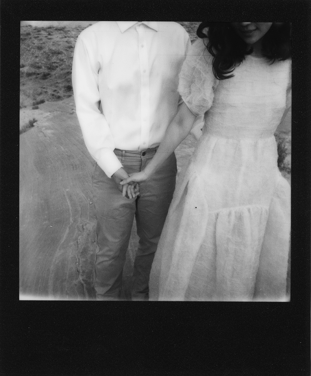 Black bordered Poloroid of people holding hands in the Utah dessert.